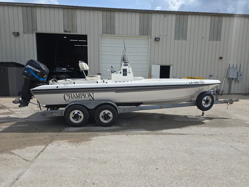 Slide: The Image of 2000 Champion 21 Bay Champ boat on trailer, parked outside a warehouse. - 7