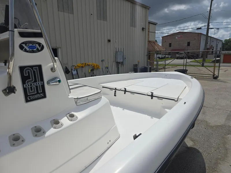 Slide: The Image of 2000 Champion 21 Bay Champ boat docked outdoors near industrial buildings. - 9