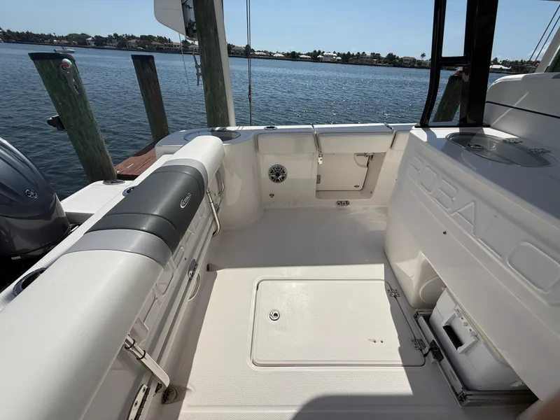 Slide: The Image of 2023 Robalo R272 Center Console boat interior with seating and storage, docked by the water. - 16