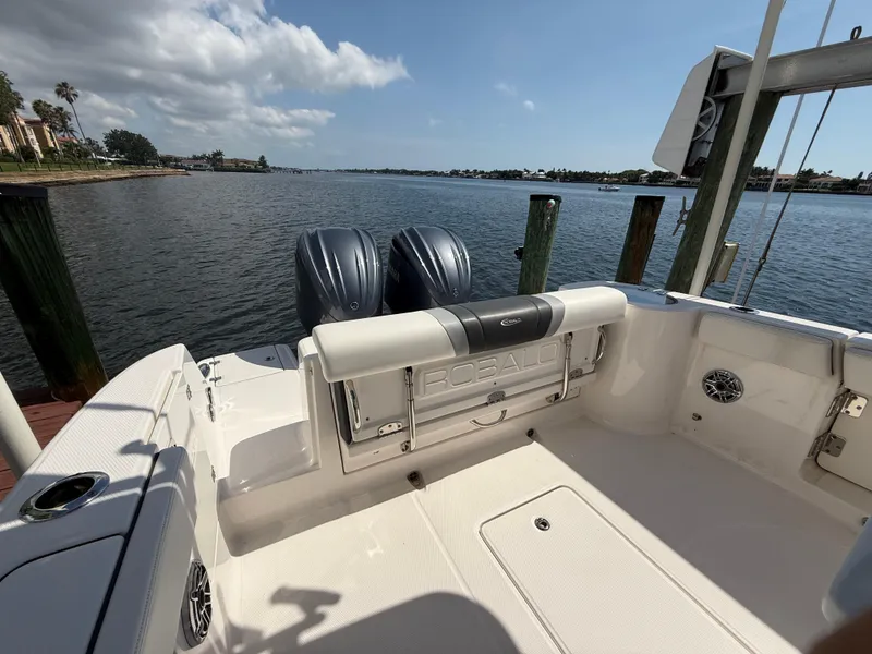 Slide: The Image of 2023 Robalo R272 Center Console boat with dual engines, docked by a scenic waterfront. - 17