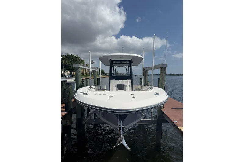 Slide: The Image of 2023 Robalo R272 Center Console boat docked by the water under a cloudy sky. - 2