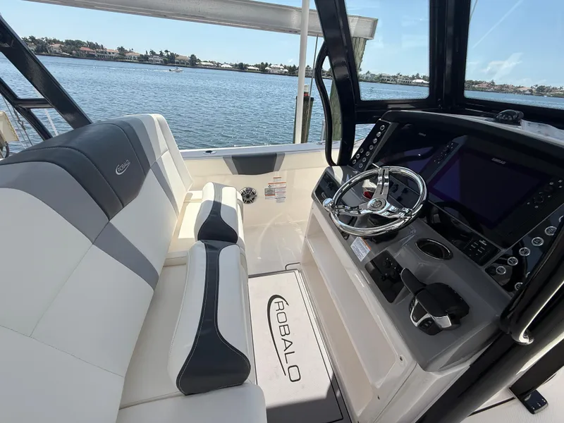 Slide: The Image of 2023 Robalo R272 Center Console boat interior with steering wheel and seating, overlooking water. - 26