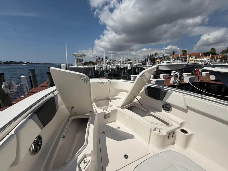 Slide: The Image of 2023 Robalo R272 Center Console boat docked, open storage compartments, sunny marina background. - 34