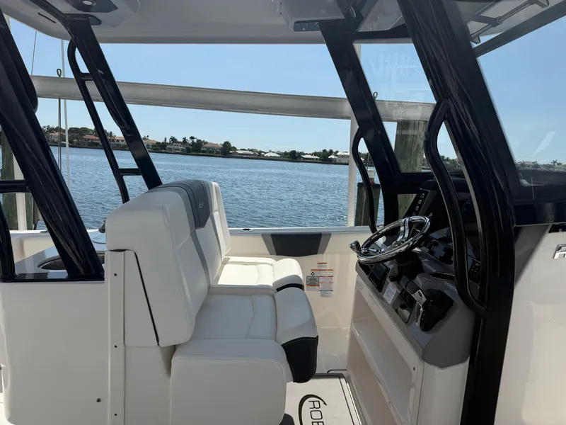Slide: The Image of 2023 Robalo R272 Center Console boat interior with white seating and steering wheel, overlooking water. - 8
