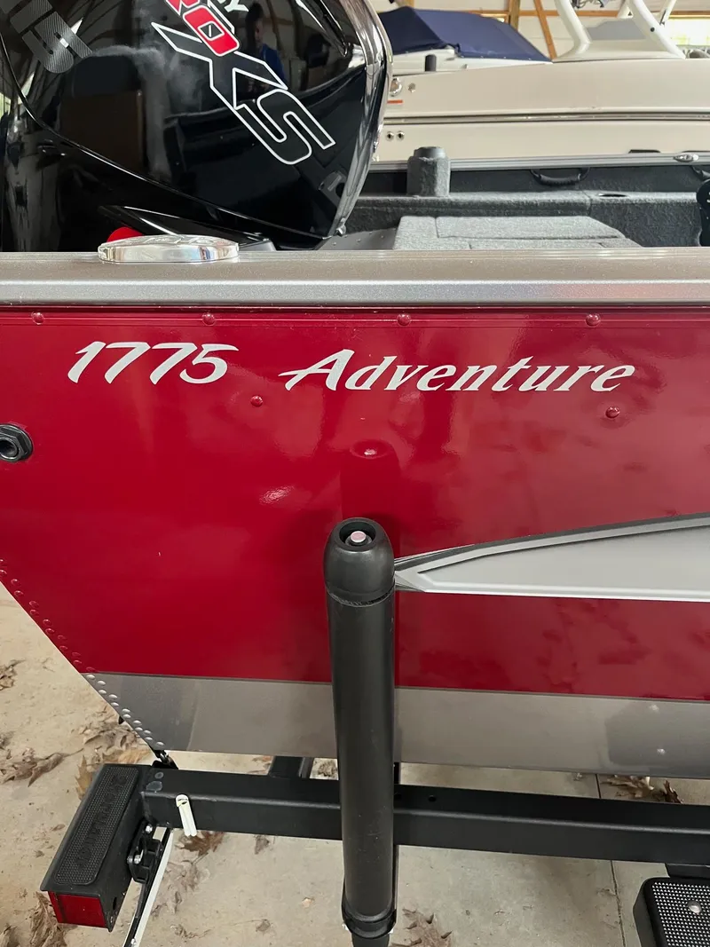 Slide: The Image of 2019 Lund 1775 Adventure Sport boat with red exterior and visible motor. - 10
