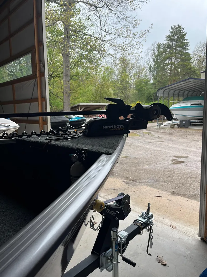 Slide: The Image of 2019 Lund 1775 Adventure Sport boat in a garage, featuring a Minn Kota trolling motor. - 4