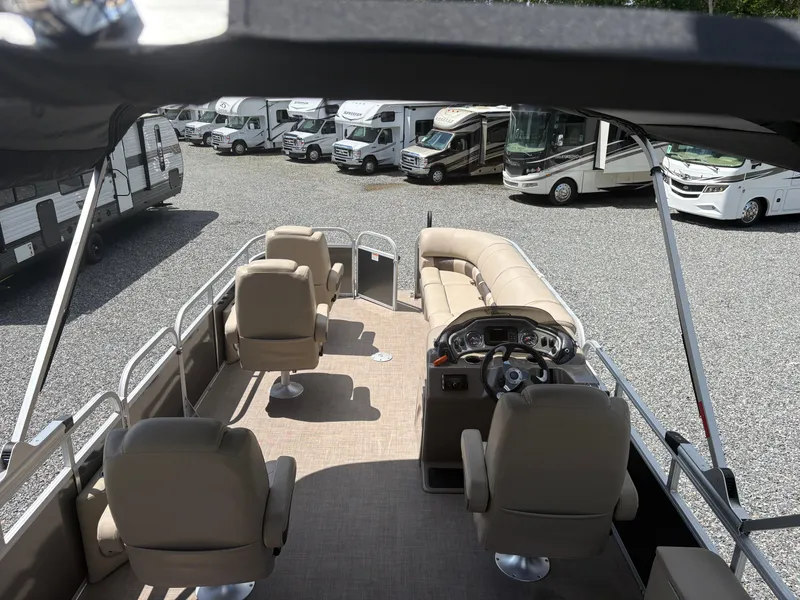 Slide: The Image of 2022 Sun Tracker Party Barge 24 DLX pontoon boat with spacious seating and helm, parked near RVs. - 21