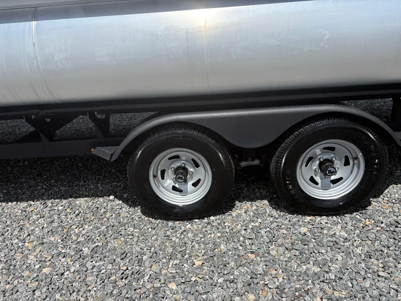Slide: The Image of Trailer wheels of 2022 Sun Tracker Party Barge 24 DLX on gravel surface. - 26
