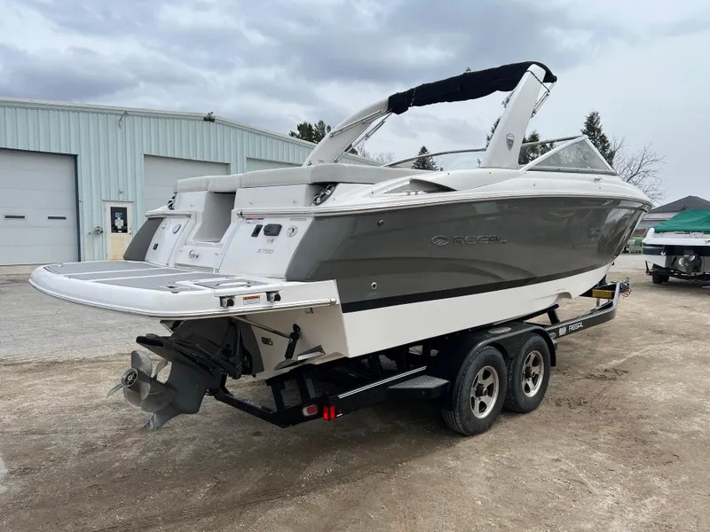 Slide: The Image of 2017 Regal 2700 boat on trailer, parked near industrial building under cloudy sky. - 3
