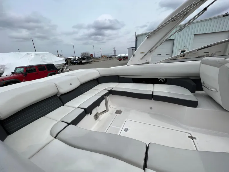 Slide: The Image of 2017 Regal 2700 boat interior with spacious seating, docked near industrial buildings under cloudy skies. - 9