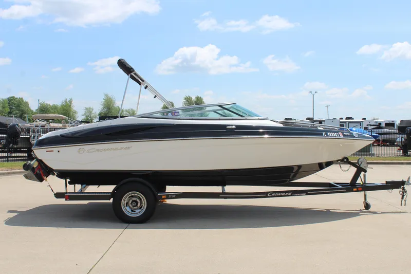 Slide: The Image of 2012 Crownline 21 SS boat on trailer, parked outdoors under a clear sky. - 4