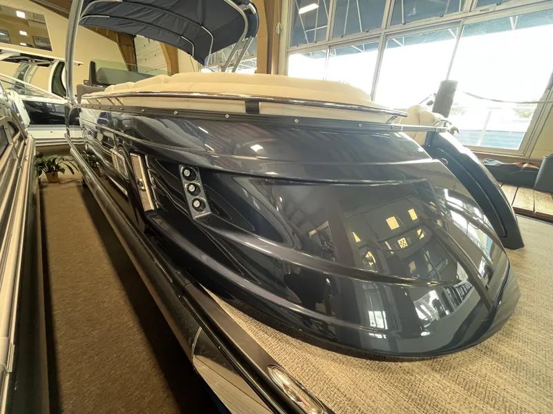 Slide: The Image of 2025 Bennington 25QXSBA pontoon boat in showroom, sleek design, luxury features. - 10