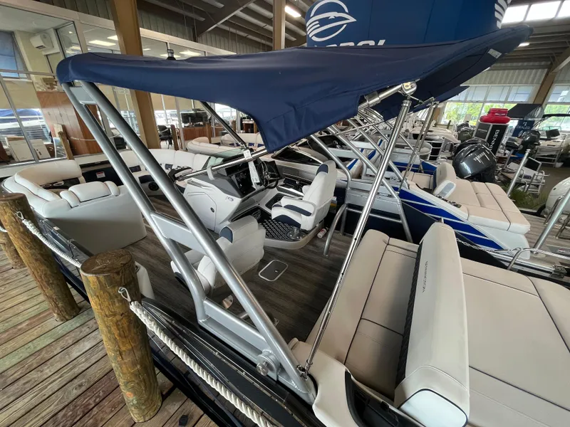 Slide: The Image of 2025 Bennington 25QXSBA pontoon boat with canopy, docked indoors. - 2