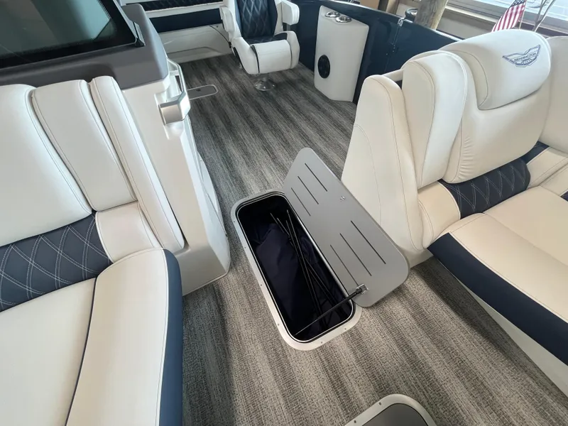 Slide: The Image of 2025 Bennington 25QXSBA boat interior with open storage compartment and luxurious seating. - 22