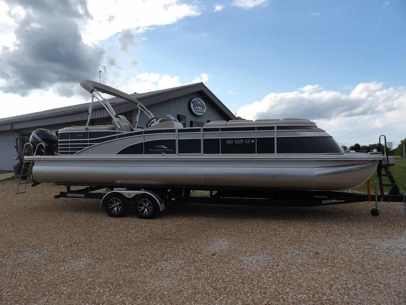 Slide: The Image of 2016 Bennington 2874 QSR pontoon boat on trailer, parked outdoors under cloudy sky. - 1
