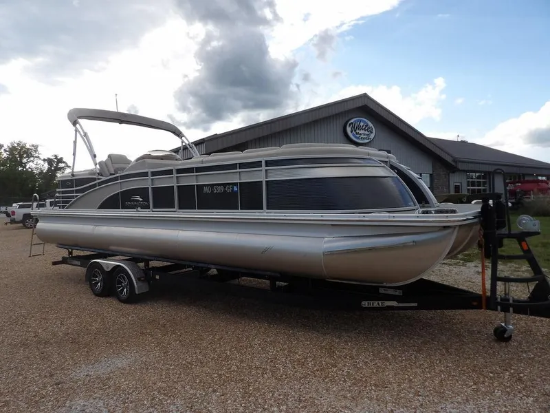 Slide: The Image of 2016 Bennington 2874 QSR pontoon boat on trailer, parked outside a building. - 2