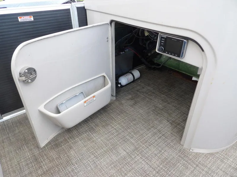 Slide: The Image of 2016 Bennington 2874 QSR boat interior storage compartment with open door and visible equipment. - 31