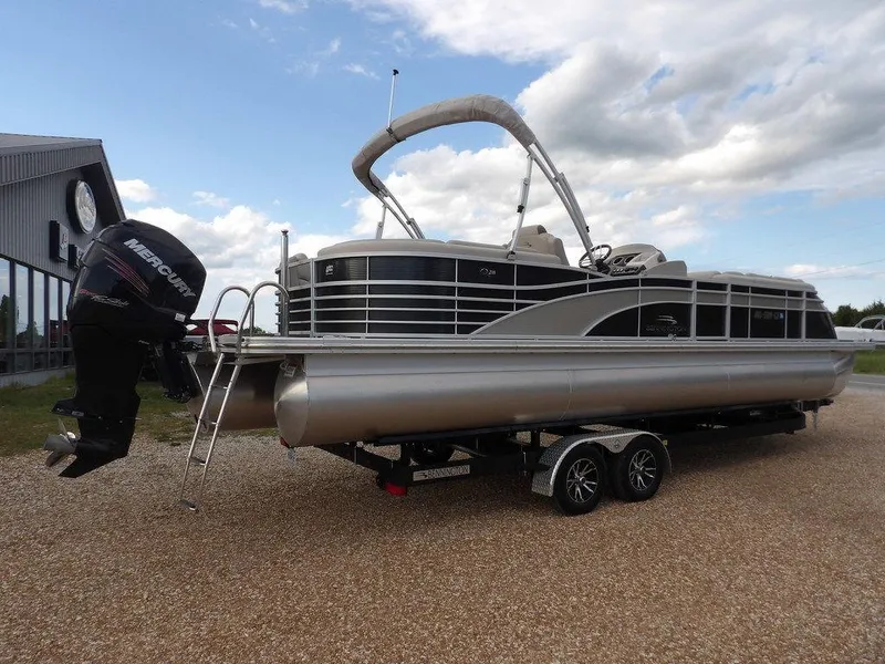 Slide: The Image of 2016 Bennington 2874 QSR pontoon boat on trailer, featuring a Mercury outboard motor. - 7