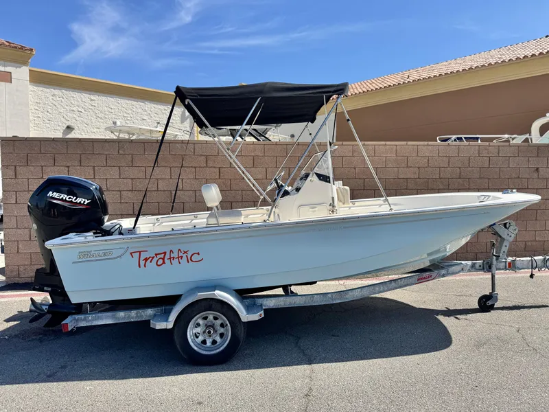 Slide: The Image of 2021 Boston Whaler 170 Montauk boat on trailer, featuring a Mercury engine and black canopy. - 0