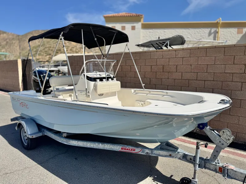 Slide: The Image of 2021 Boston Whaler 170 Montauk boat on trailer with black canopy, parked outdoors. - 1