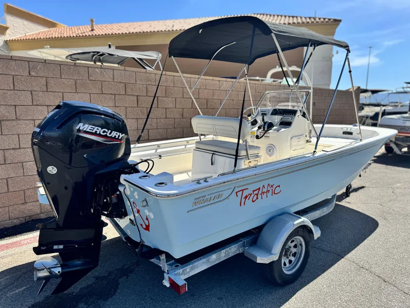 Slide: The Image of 2021 Boston Whaler 170 Montauk boat with Mercury engine on trailer, parked outdoors. - 5