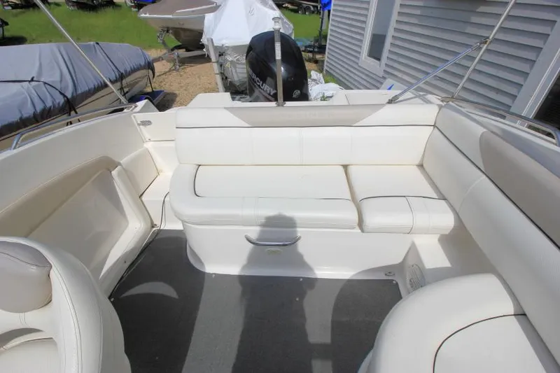 Slide: The Image of 2013 Bayliner 190 Deck Boat interior with white seating and outdoor setting. - 11