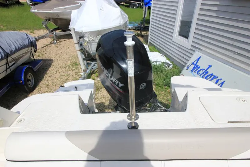 Slide: The Image of 2013 Bayliner 190 Deck Boat with Mercury outboard motor, parked near a building. - 12