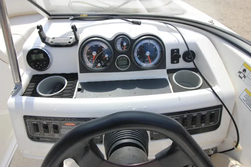 Slide: The Image of 2013 Bayliner 190 Deck Boat dashboard with gauges, cup holders, and steering wheel. - 16