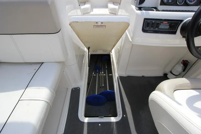 Slide: The Image of 2013 Bayliner 190 Deck Boat interior storage compartment with paddles. - 18