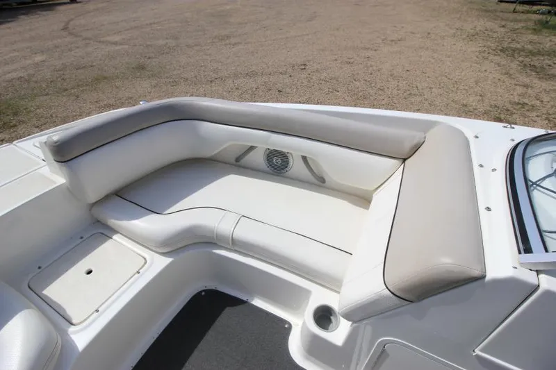 Slide: The Image of 2013 Bayliner 190 Deck Boat interior seating with beige cushions and storage compartment. - 21