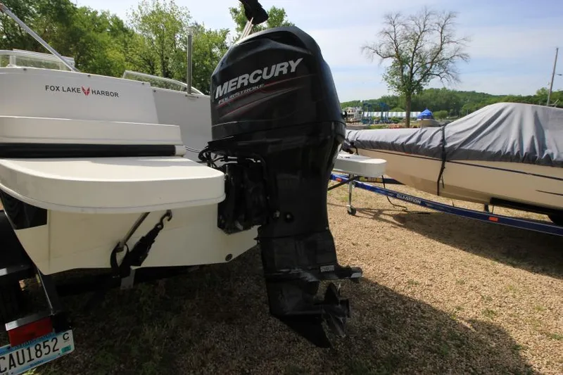 Slide: The Image of 2013 Bayliner 190 Deck Boat with Mercury outboard motor, parked on gravel. - 7