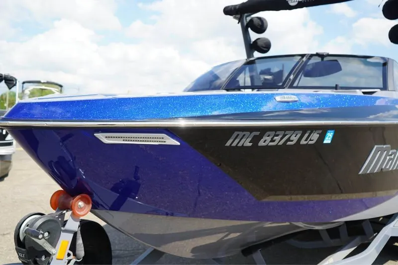 Slide: The Image of 2022 Malibu Wakesetter 25 LSV boat with blue and black exterior, parked on a trailer. - 10