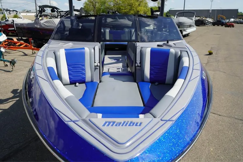 Slide: The Image of 2022 Malibu Wakesetter 25 LSV boat with blue and gray seating, docked outdoors. - 12