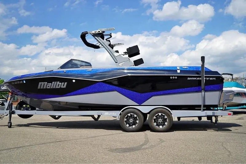 Slide: The Image of 2022 Malibu Wakesetter 25 LSV boat on trailer under blue sky. - 2