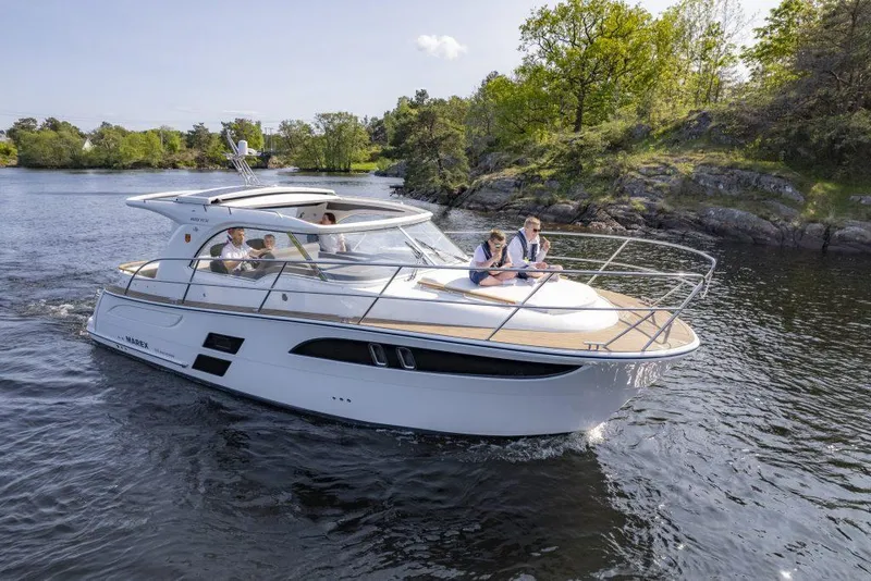 Slide: The Image of 2025 Marex 310 Sun Cruiser on a scenic waterway with passengers enjoying the view. - 16