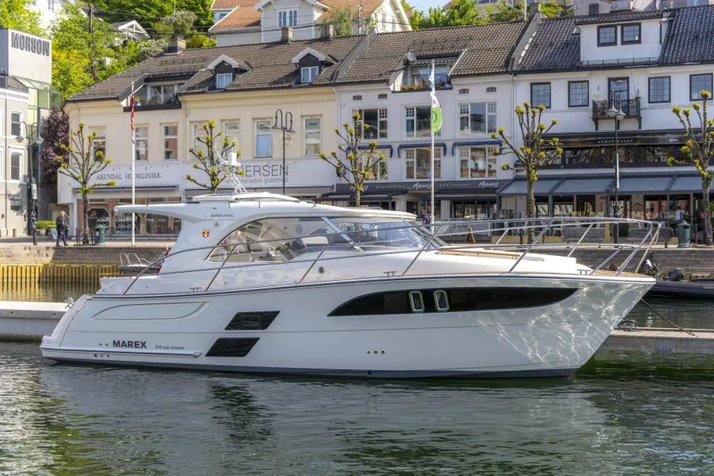 Slide: The Image of 2025 Marex 310 Sun Cruiser yacht docked in a scenic harbor setting. - 17