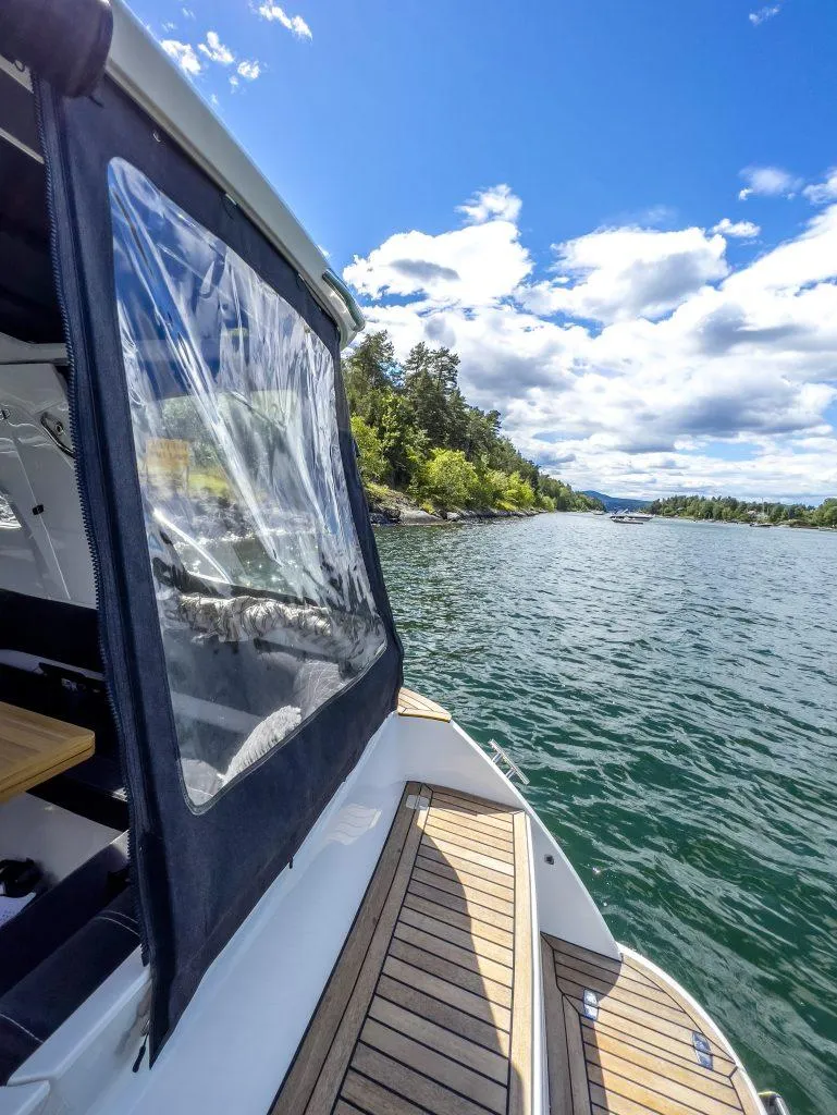 Slide: The Image of 2025 Marex 310 Sun Cruiser on scenic lake with clear skies and lush shoreline. - 18