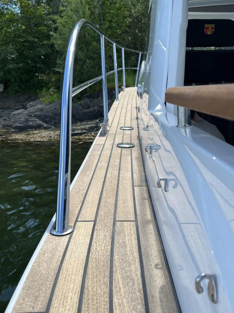 Slide: The Image of 2025 Marex 310 Sun Cruiser deck with sleek railing and wood finish. - 20