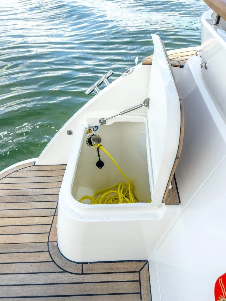 Slide: The Image of 2025 Marex 310 Sun Cruiser storage compartment with yellow cable on teak deck. - 22
