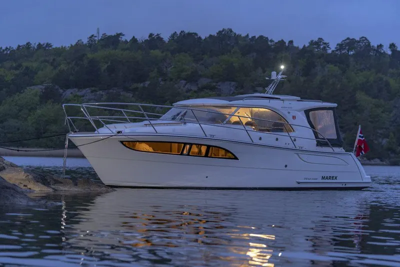 Slide: The Image of 2025 Marex 310 Sun Cruiser yacht anchored on serene water at dusk. - 32