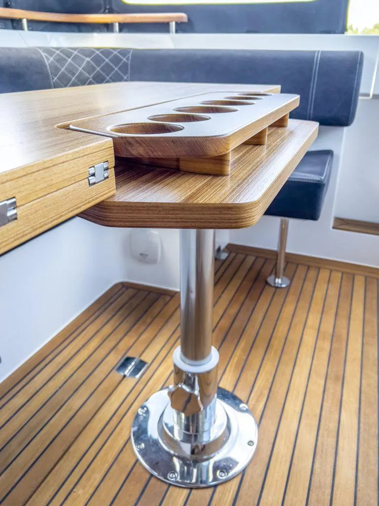 Slide: The Image of 2025 Marex 310 Sun Cruiser interior with wooden table and cup holders. - 33