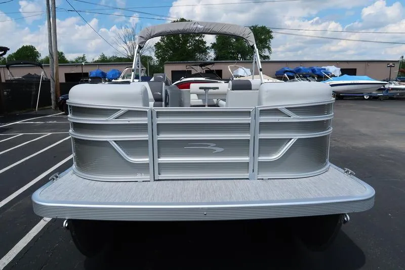 Slide: The Image of 2025 Bennington S L-Bench 20 SL pontoon boat, silver exterior, parked outdoors. - 18
