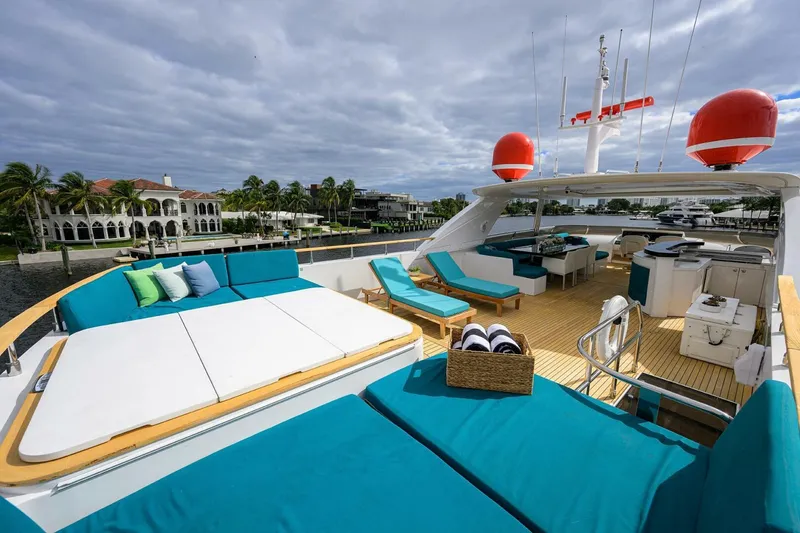 Slide: The Image of Luxurious 2009 Princess 95 yacht deck with sun loungers and seating, docked by waterfront homes. - 19