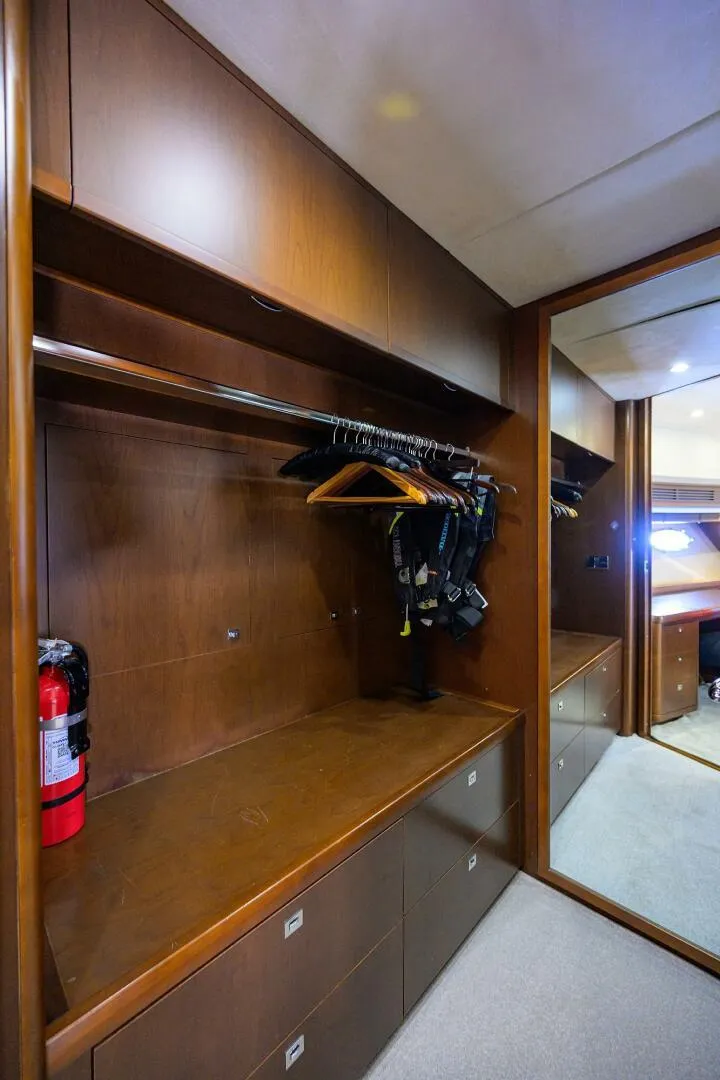 Slide: The Image of Luxurious wooden closet interior on a 2009 Princess 95 yacht, featuring ample storage and a fire extinguisher. - 45
