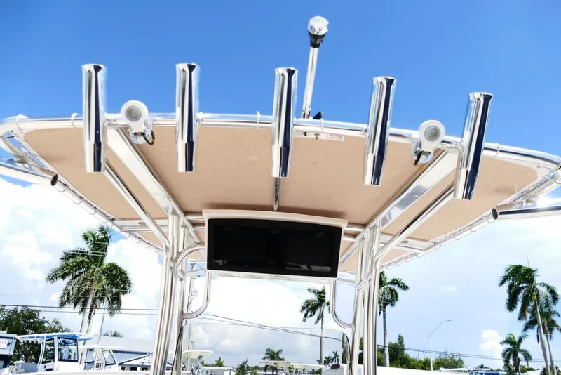 Slide: The Image of 2026 Pioneer 222 Islander boat with rod holders and canopy under a clear blue sky. - 11