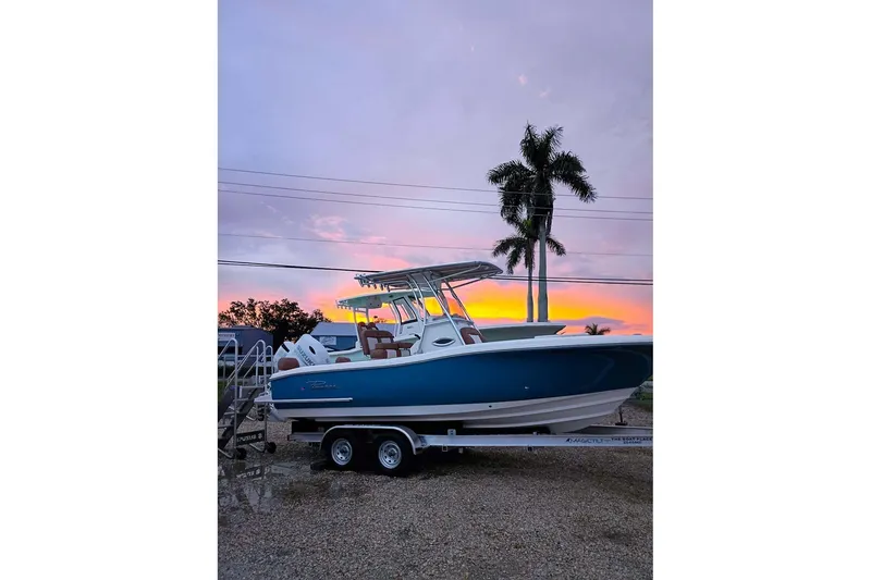Slide: The Image of 2026 Pioneer 222 Islander boat on trailer at sunset with palm trees. - 2