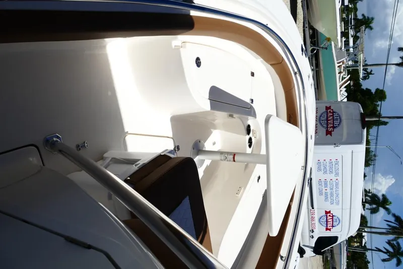 Slide: The Image of 2026 Pioneer 222 Islander boat interior with seating and storage, parked near a service van. - 21