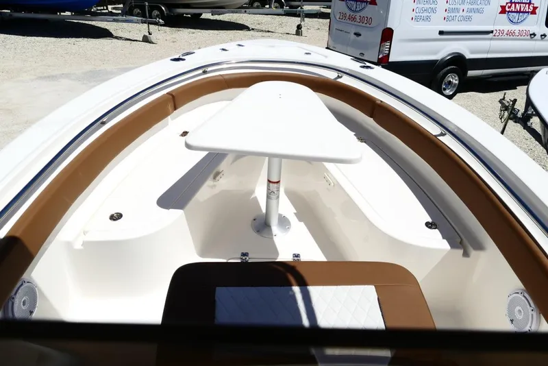 Slide: The Image of 2026 Pioneer 222 Islander boat interior with seating and table, parked outdoors. - 22