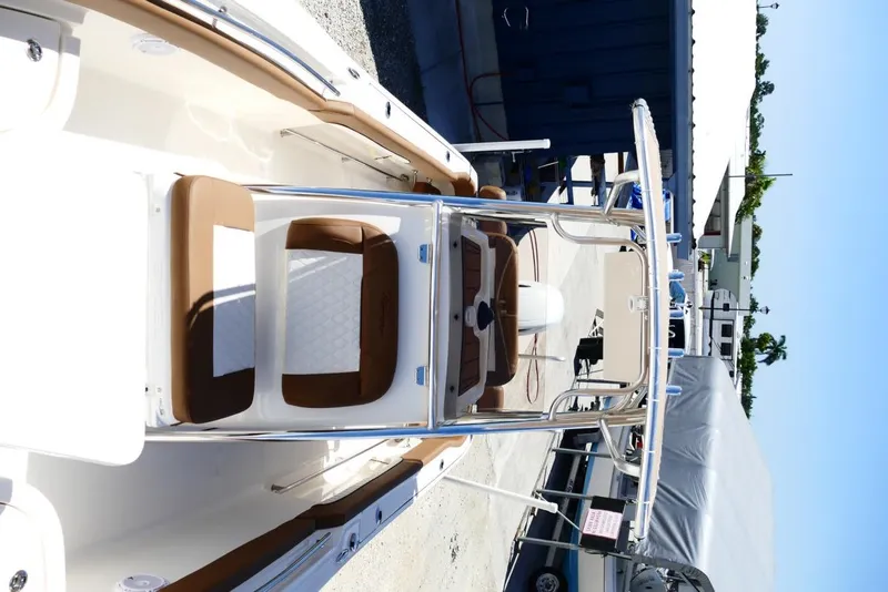 Slide: The Image of 2026 Pioneer 222 Islander boat with brown seating and sleek design in a marina setting. - 30