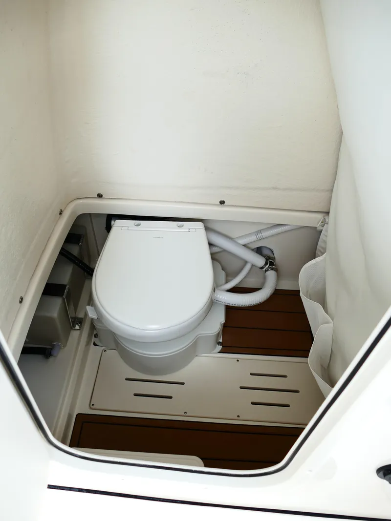 Slide: The Image of 2026 Bulls Bay 255CC boat interior with compact marine toilet and wooden flooring. - 34